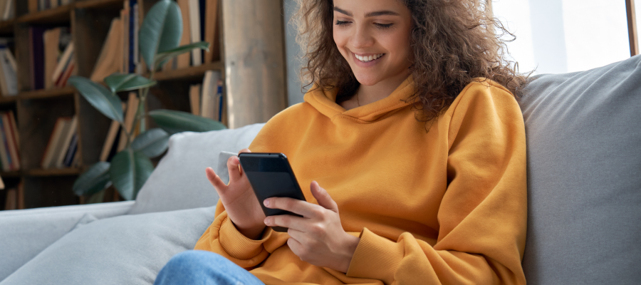 Smiling young latin woman using mobile phone app playing game,