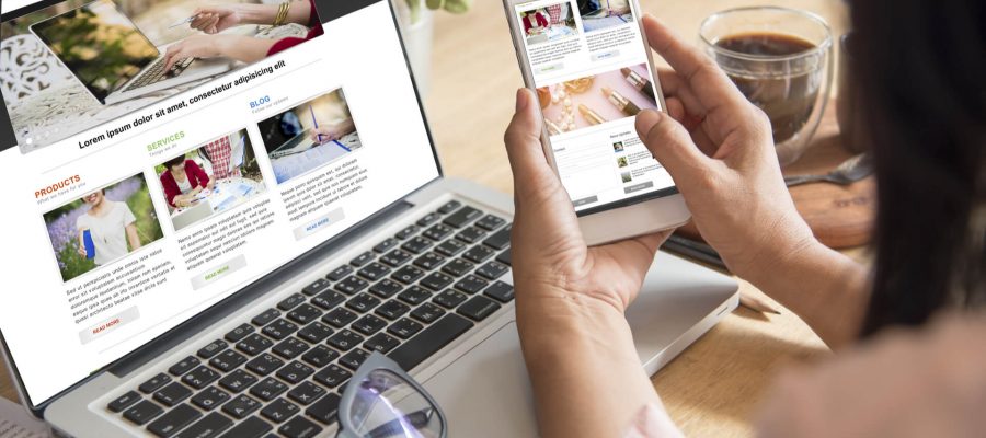 Business Owner Looking At Her Websites On A Laptop & Cell Phone